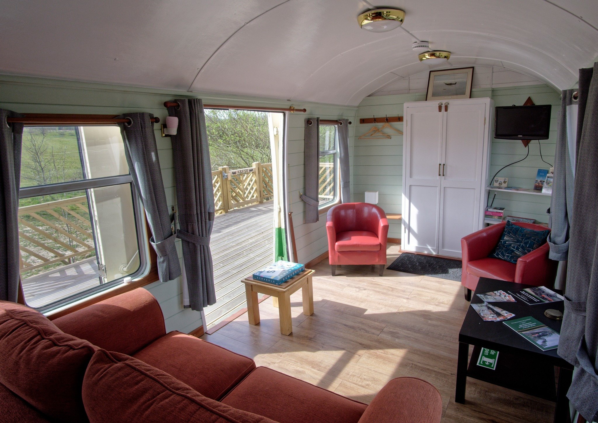 The communal area, featuring two red single chairs, a coffee table, and a red double sofa.